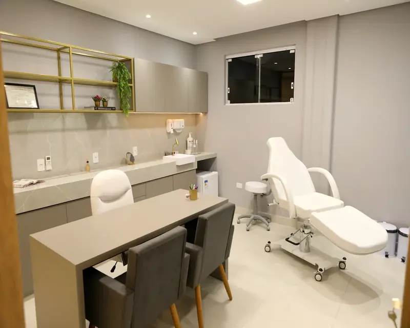 Sala de procedimentos com maca, bancada e cadeiras